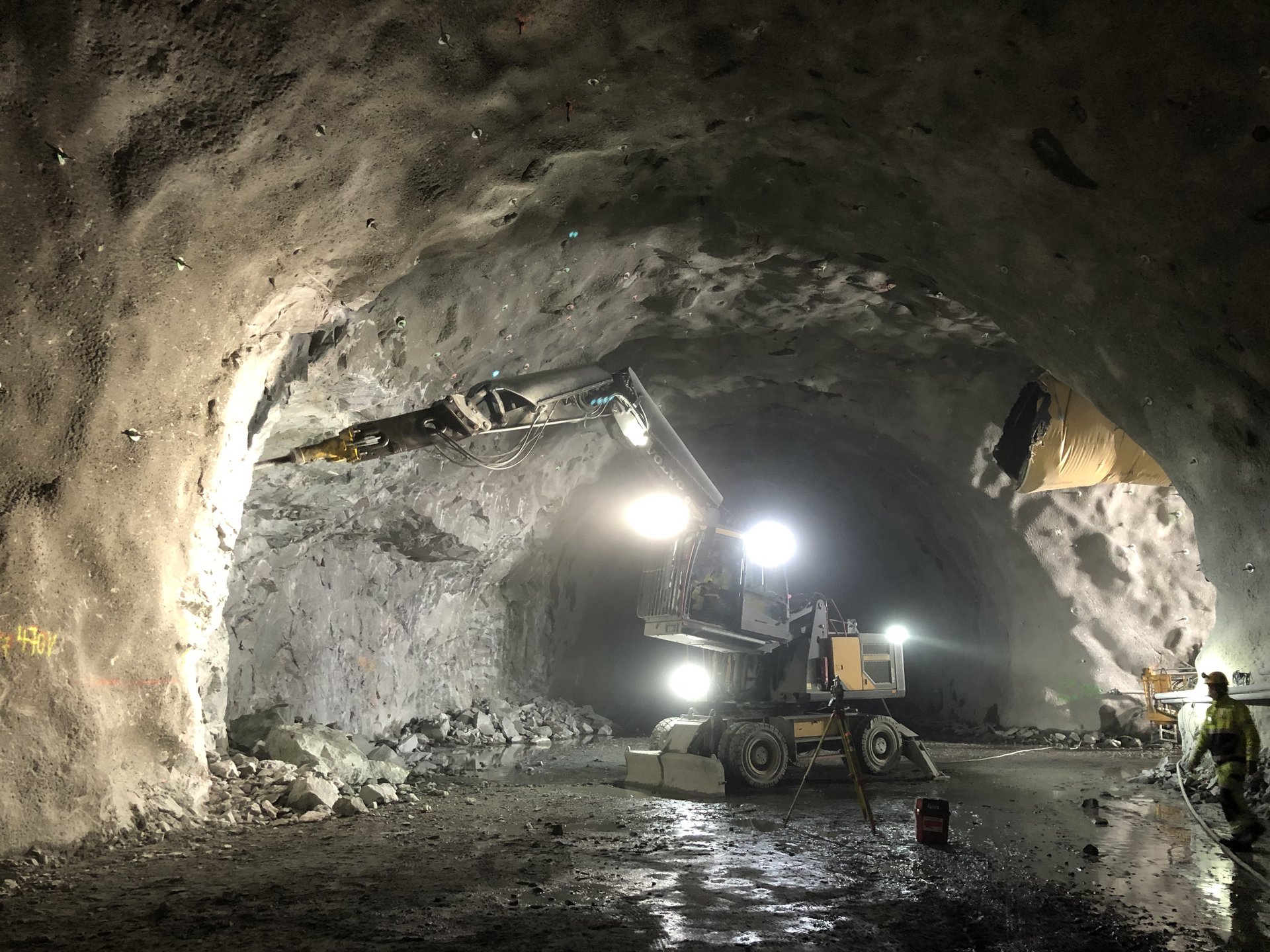 Construction worker driving a bulldozer through a tunnel. The bulldozer is a large, yellow vehicle with a shovel at the front.
