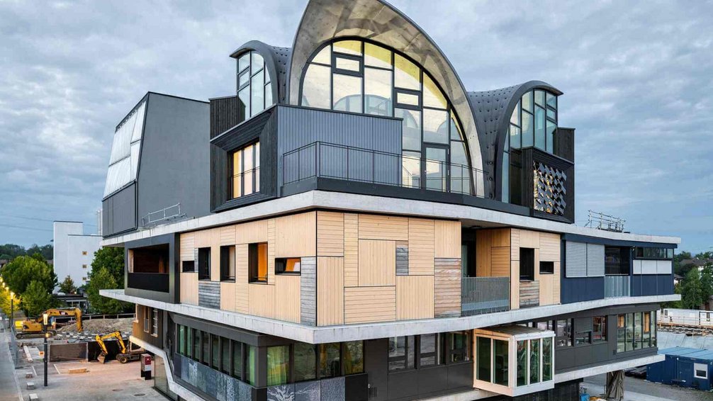 Gebäude, Teil des NEST-Forschungsgebäudes, bei der Empa, der Eidgenössischen Materialprüfungs- und Forschungsanstalt in Dübendorf. Das Gebäude ist hoch und hat ein rundes Dach. Es ist aus Glas und Metall gefertigt und hat eine moderne, minimalistische Optik. Das Gebäude wurde vom Architekturbüro Lüchinger & Egli entworfen.